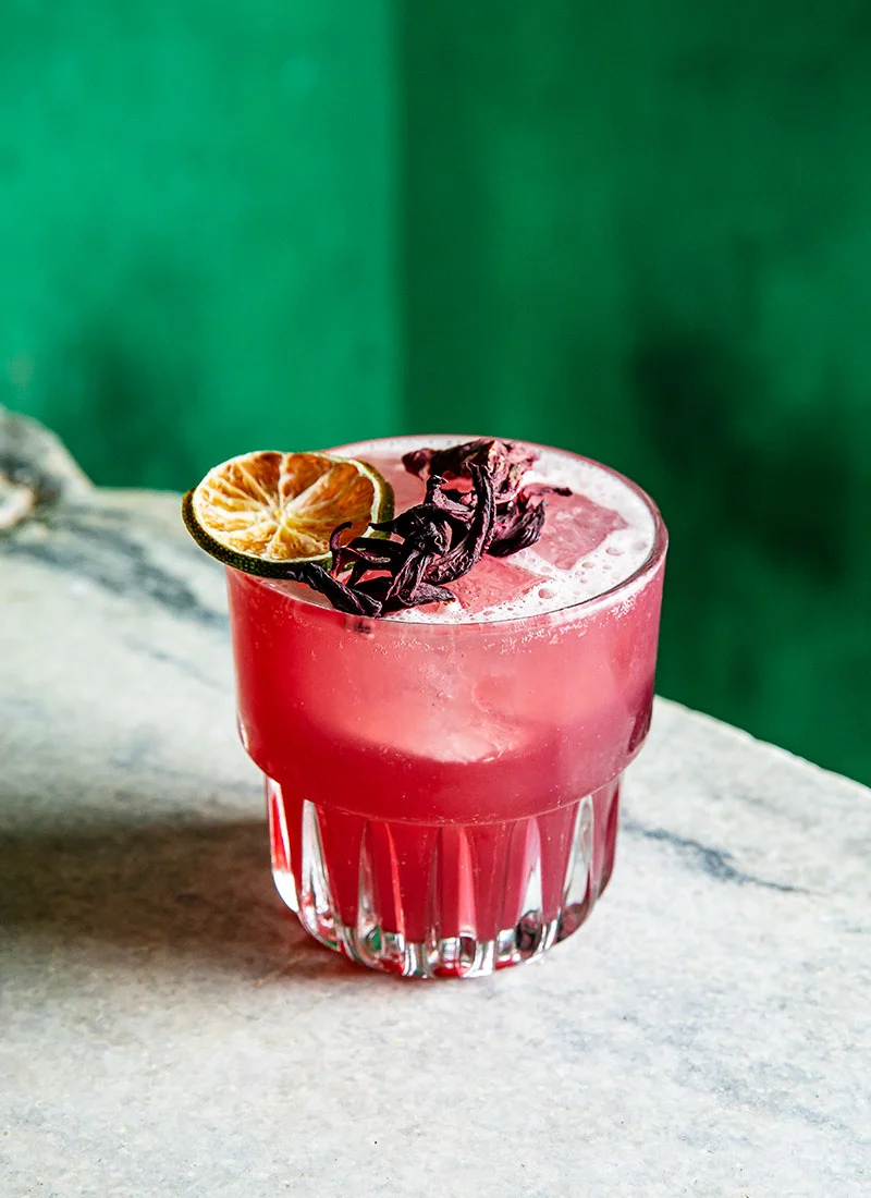 Vibrant hibiscus cocktail garnished with dried lime
