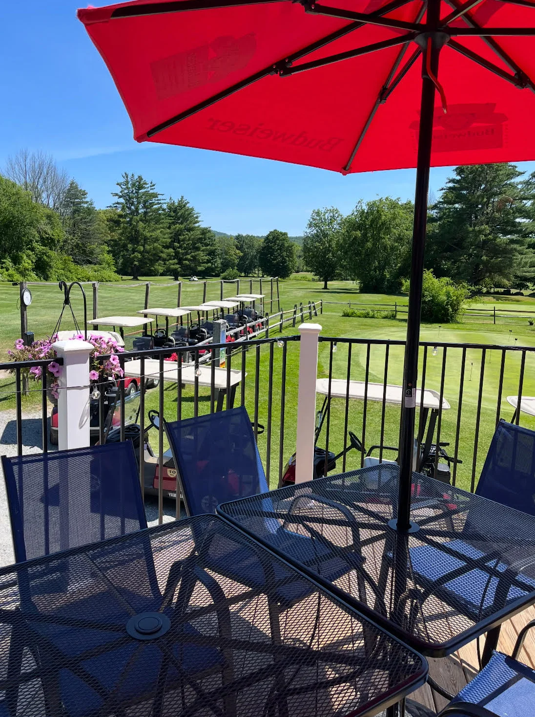 Outdoor dining area with golf course view under a red umbrella