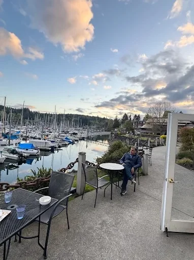 Scenic waterfront dining area with boats and clouds
