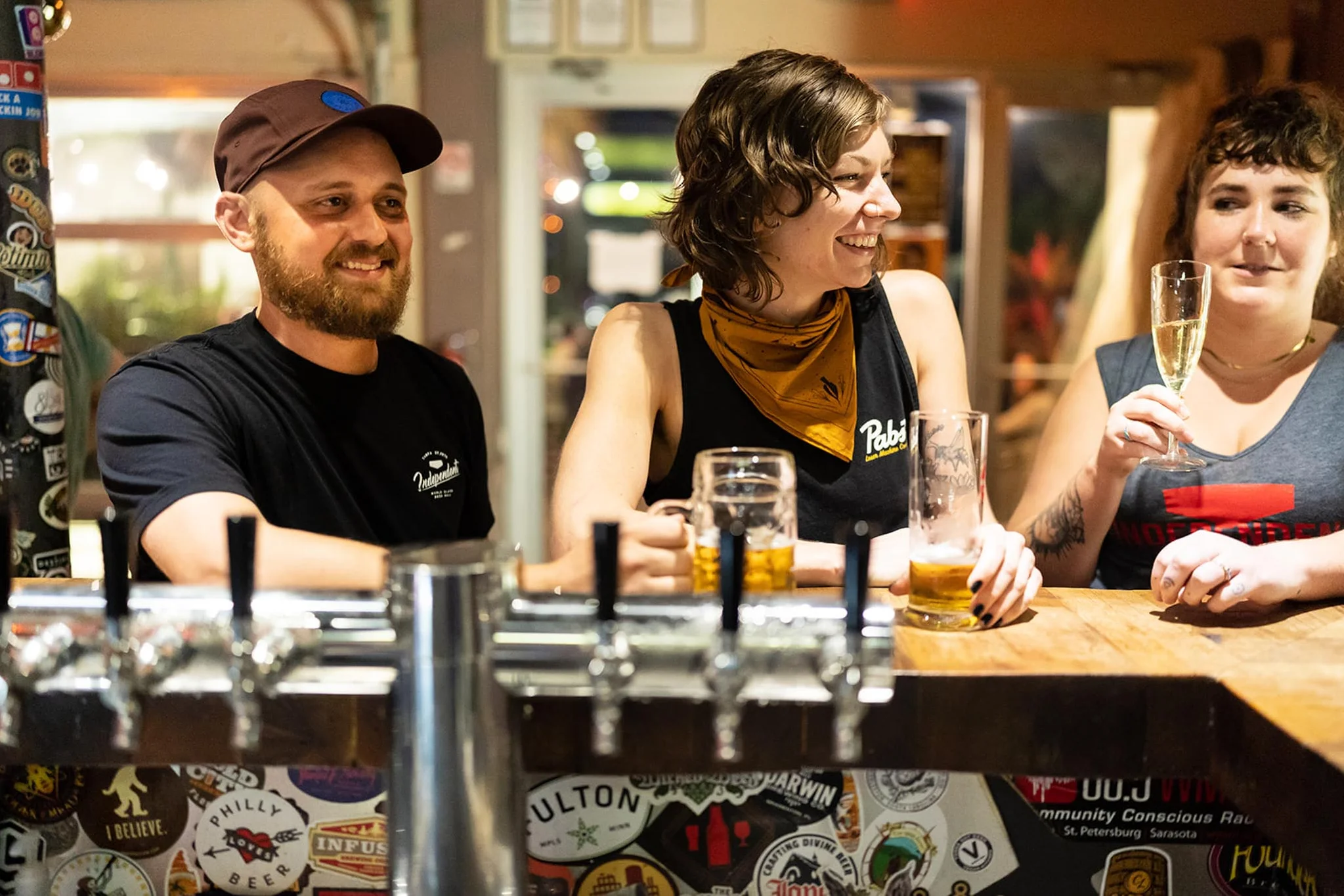Bartenders enjoying drinks at a lively bar with craft beer taps