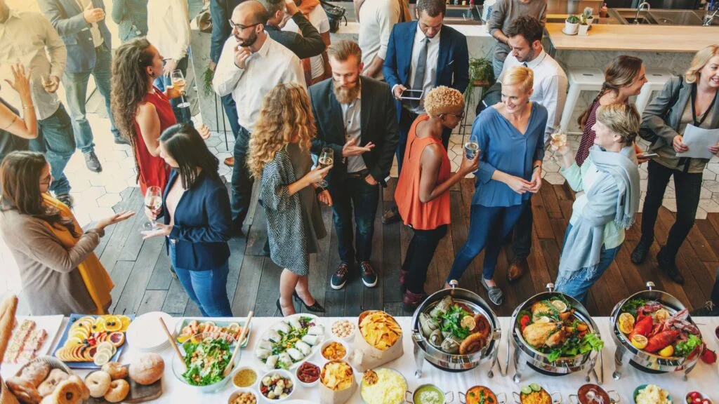 Vibrant social gathering with diverse guests enjoying a buffet spread