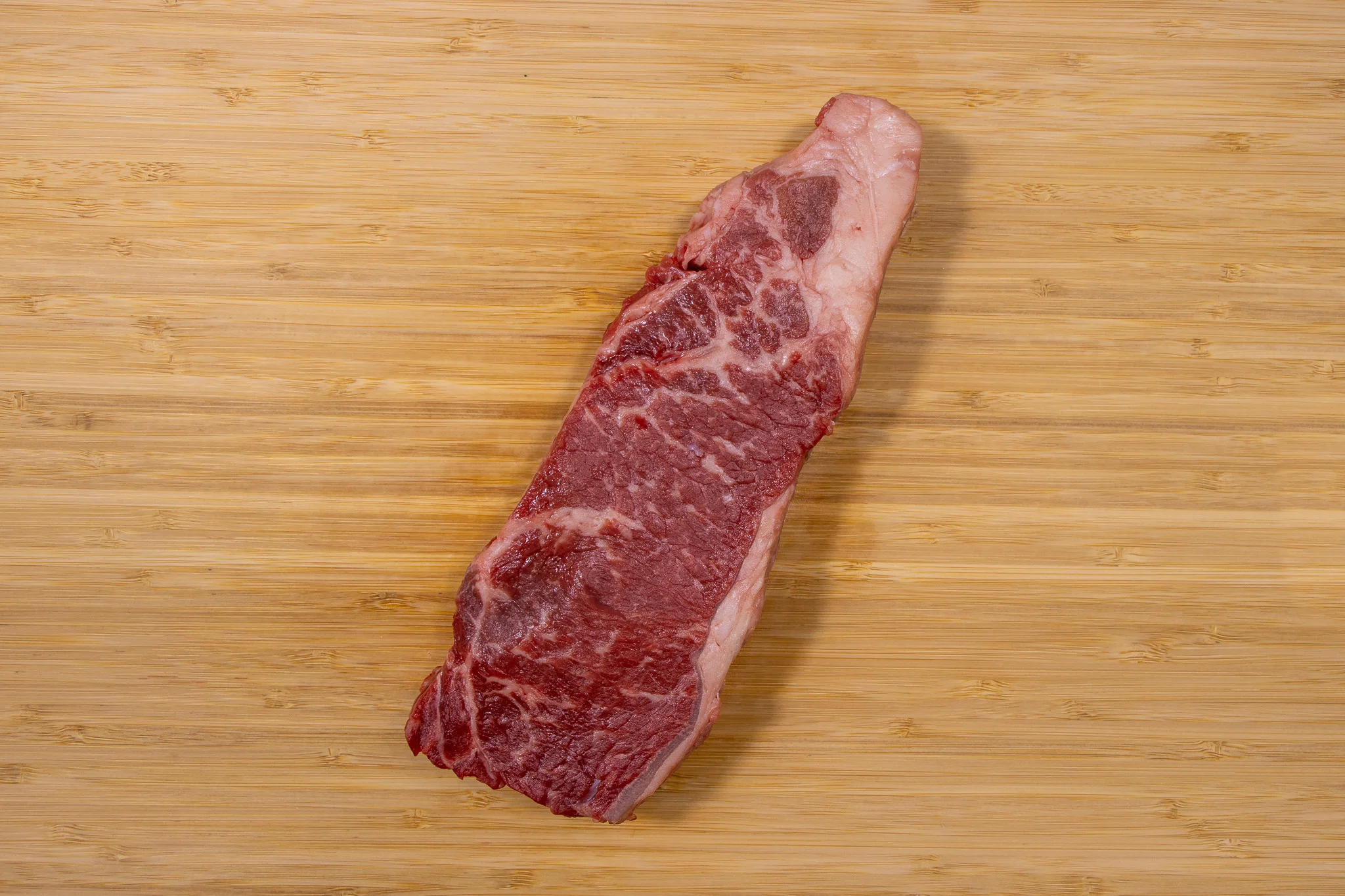 Raw ribeye steak on a wooden cutting board