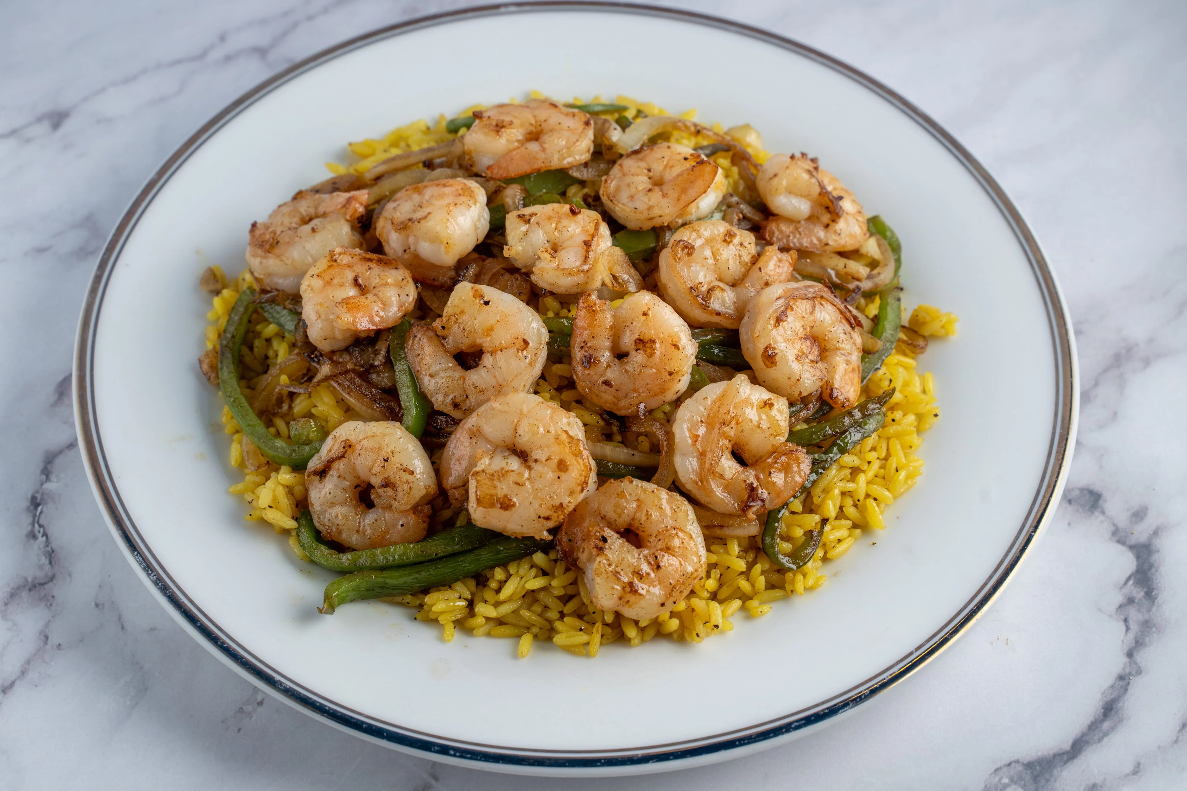 Shrimp served on yellow rice with green peppers and onions.