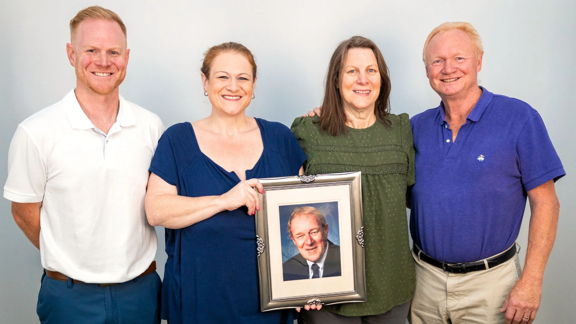 Family portrait holding a framed photo of a loved one