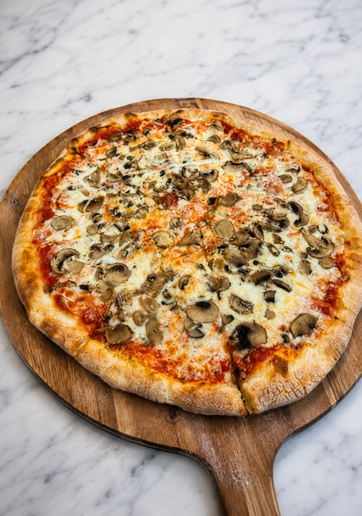 A delicious pizza topped with mushrooms and cheese, served on a wooden pizza paddle.