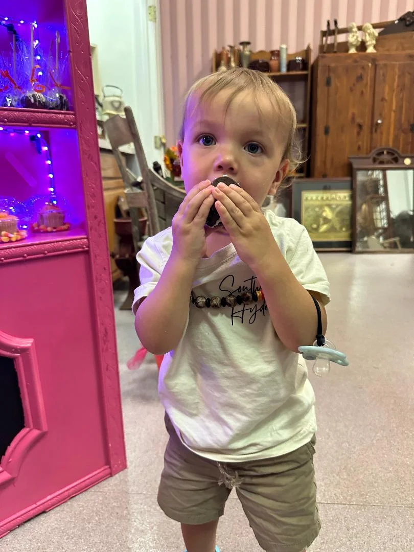 Child holding a toy in a colorful antique shop