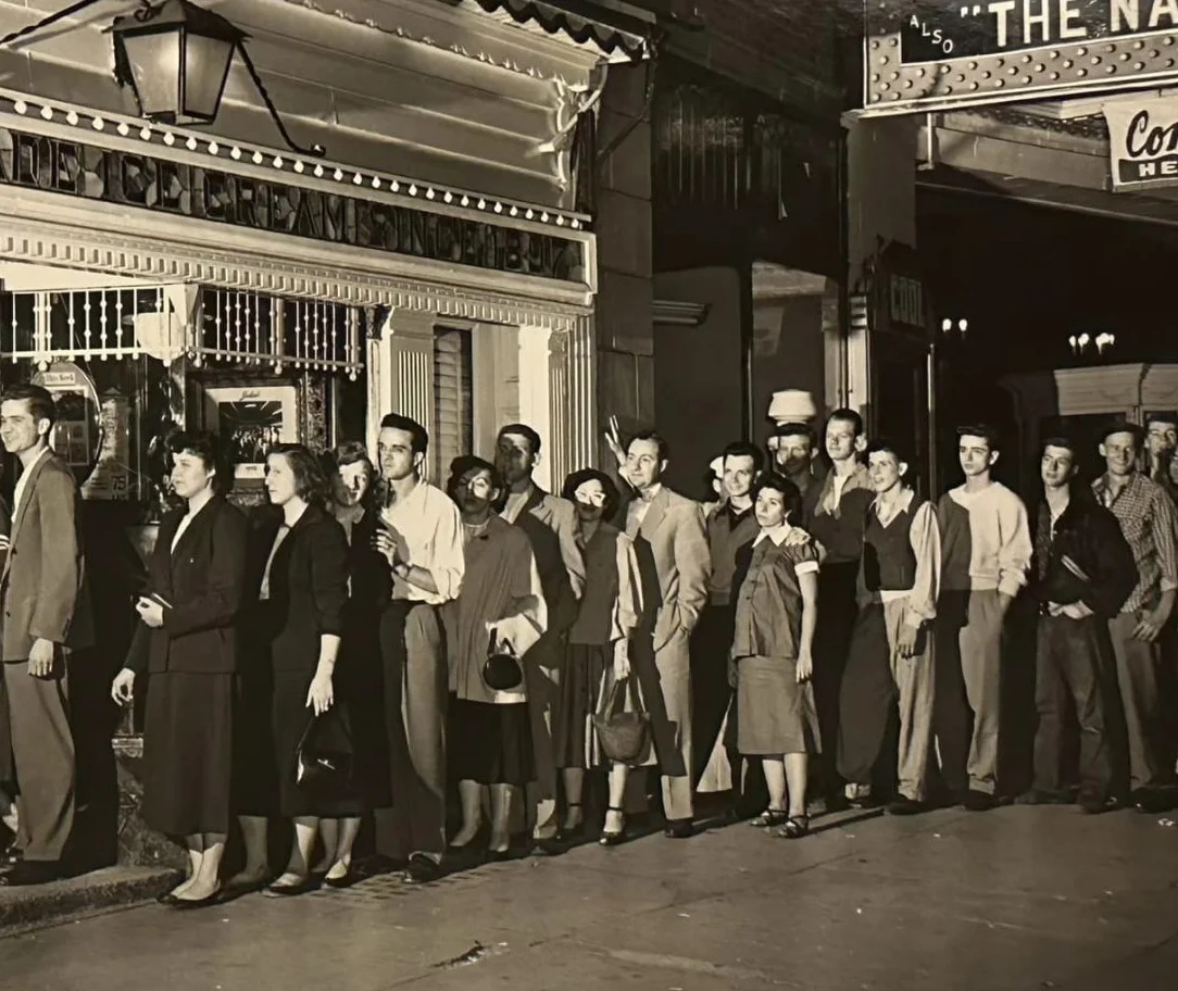 Historic restaurant exterior with a long line of patrons waiting
