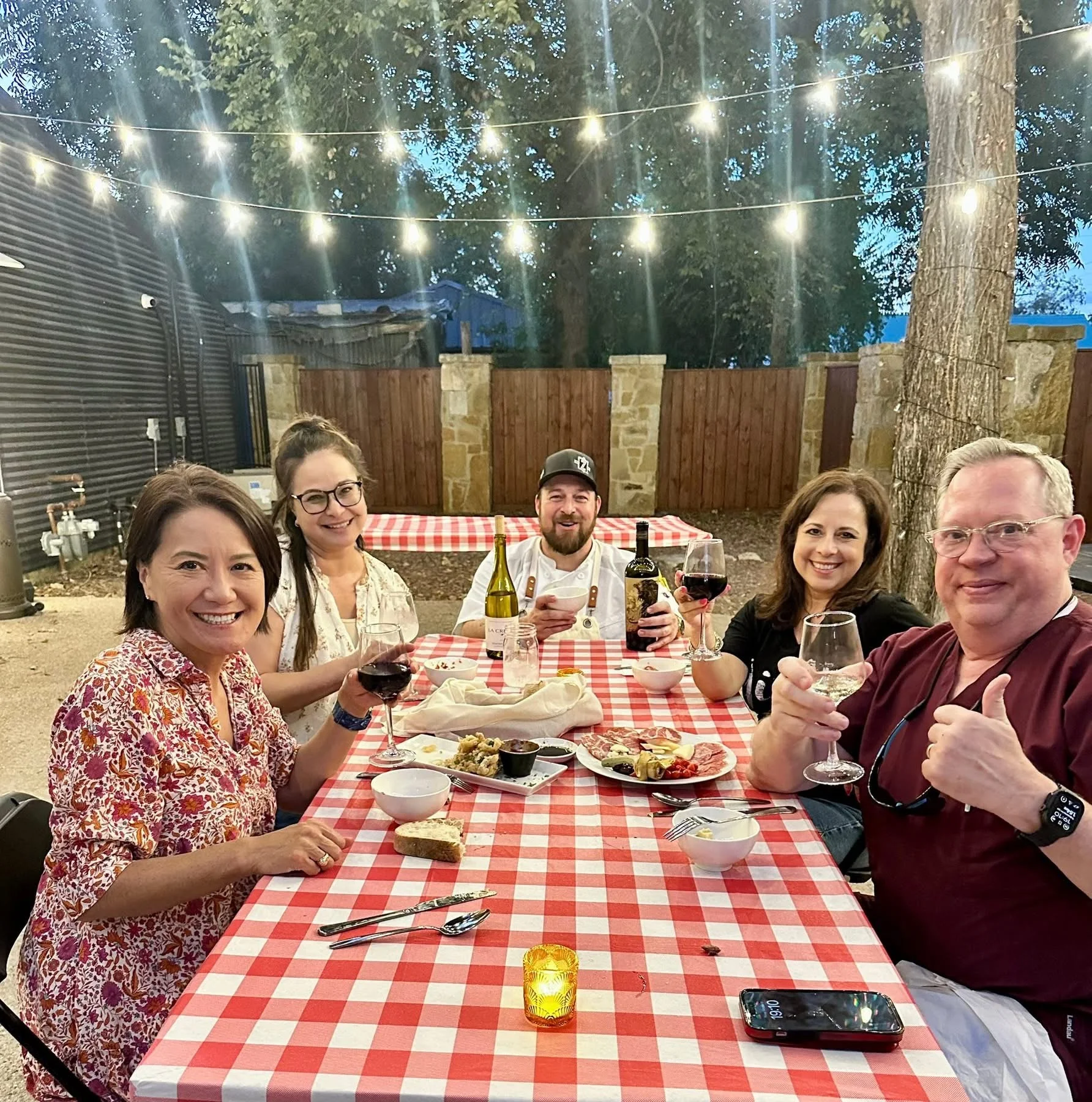 Group enjoying wine and appetizers at a cozy outdoor dining table