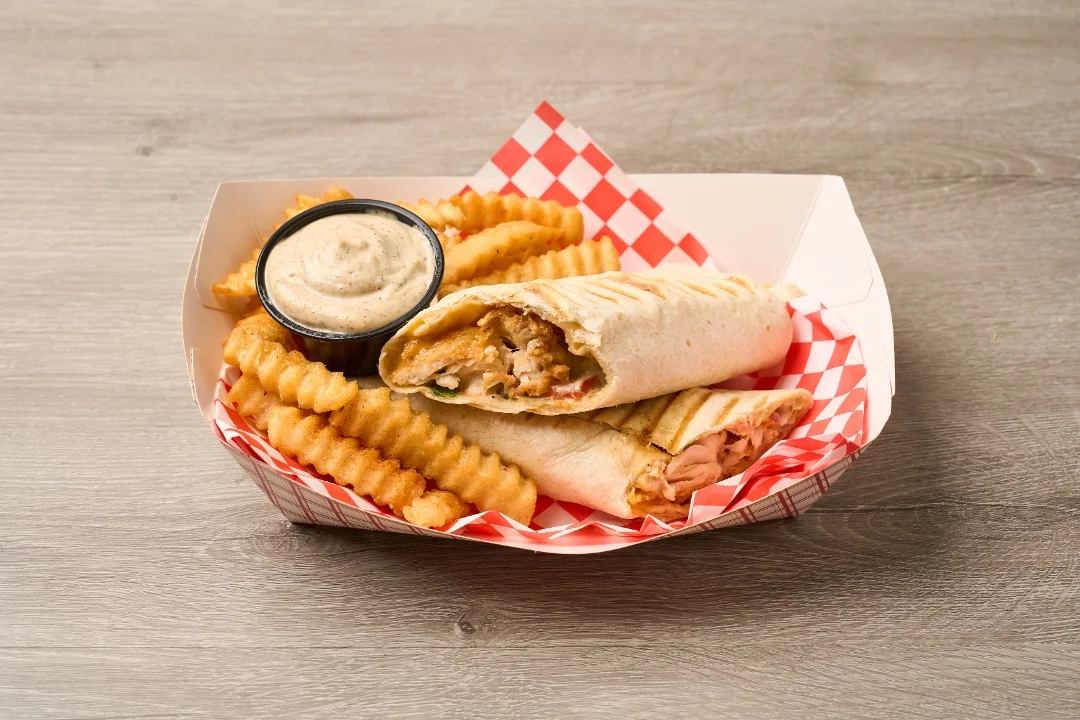 A wrapped burrito with filling, served with crinkle-cut fries and a small container of dipping sauce.