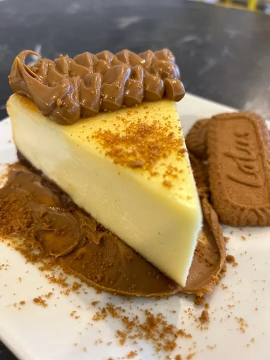 Creamy cheesecake slice with chocolate frosting and Lotus biscuit