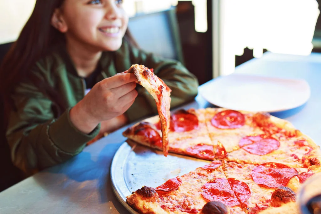 girl eating a pepperoni pizza