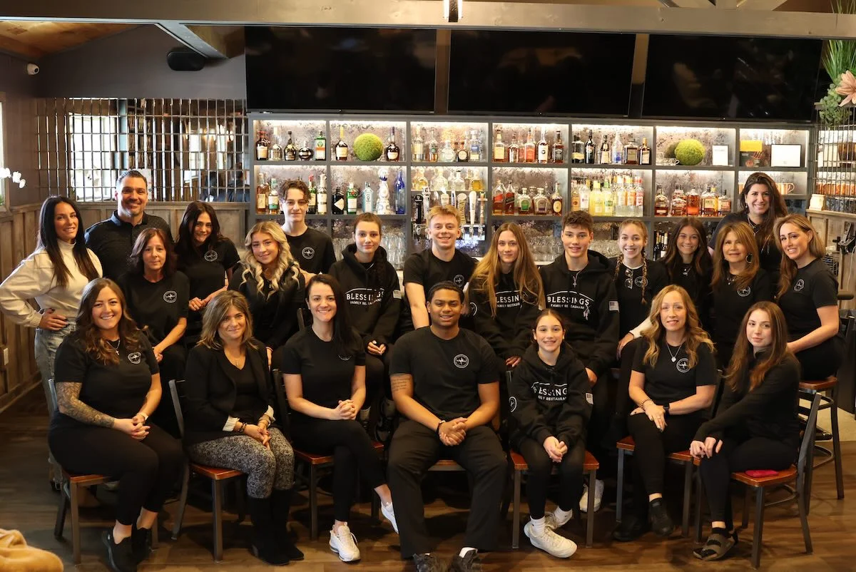 Restaurant staff posing together in a modern bar setting
