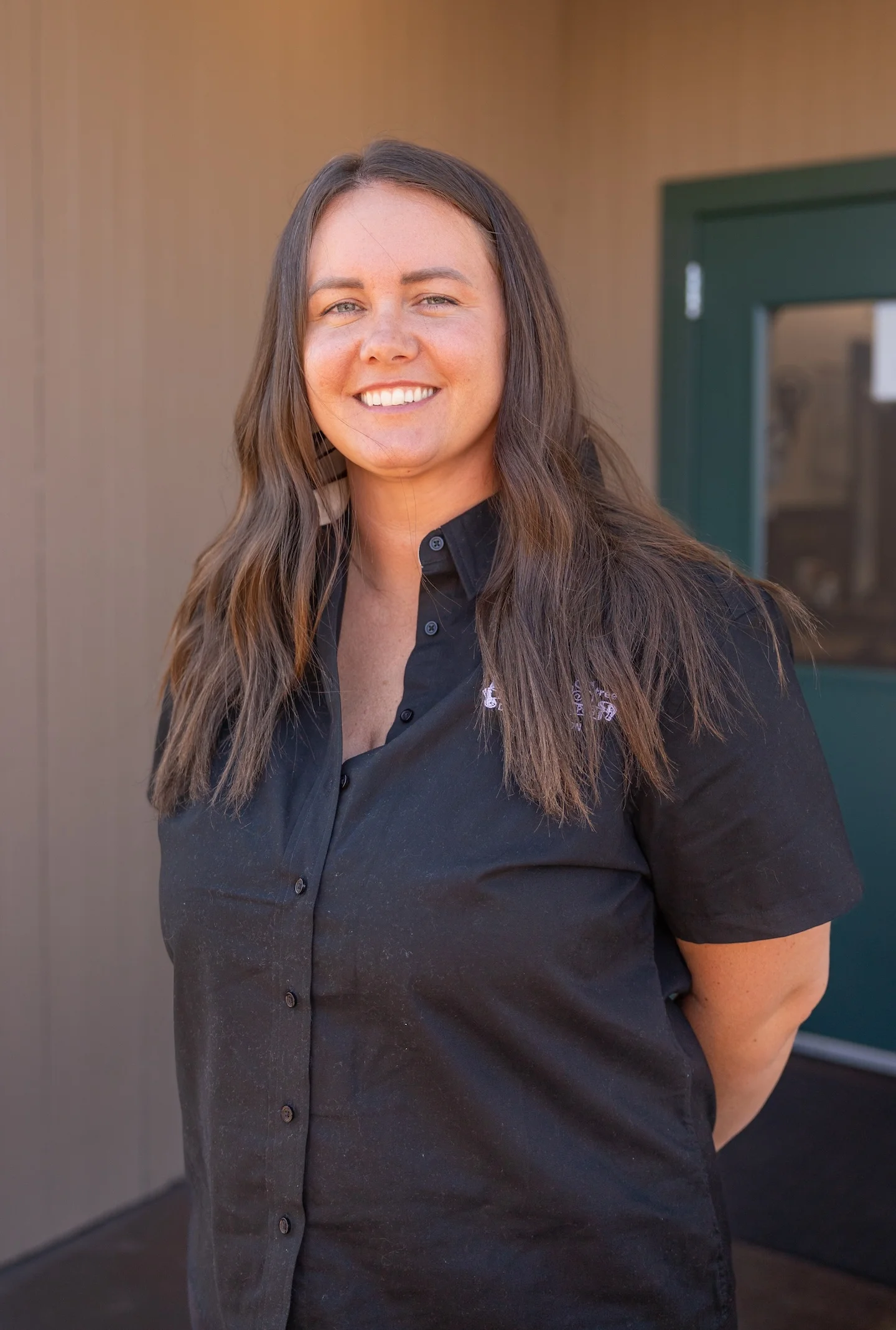 Smiling woman in a black shirt at a restaurant entrance
