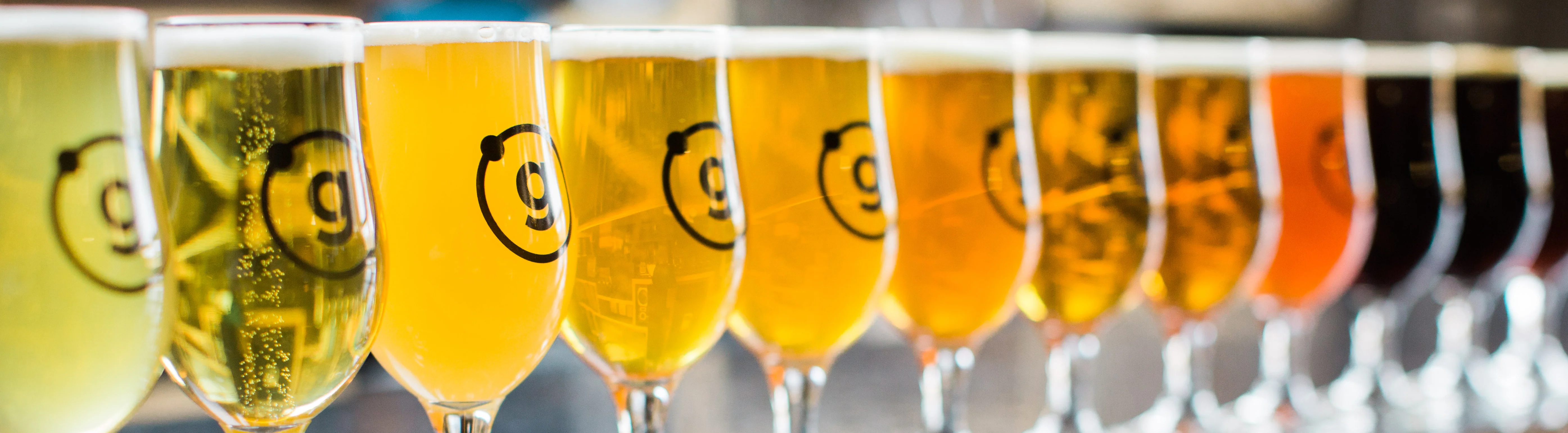 A row of colorful Gravely beer glasses on a reflective surface.