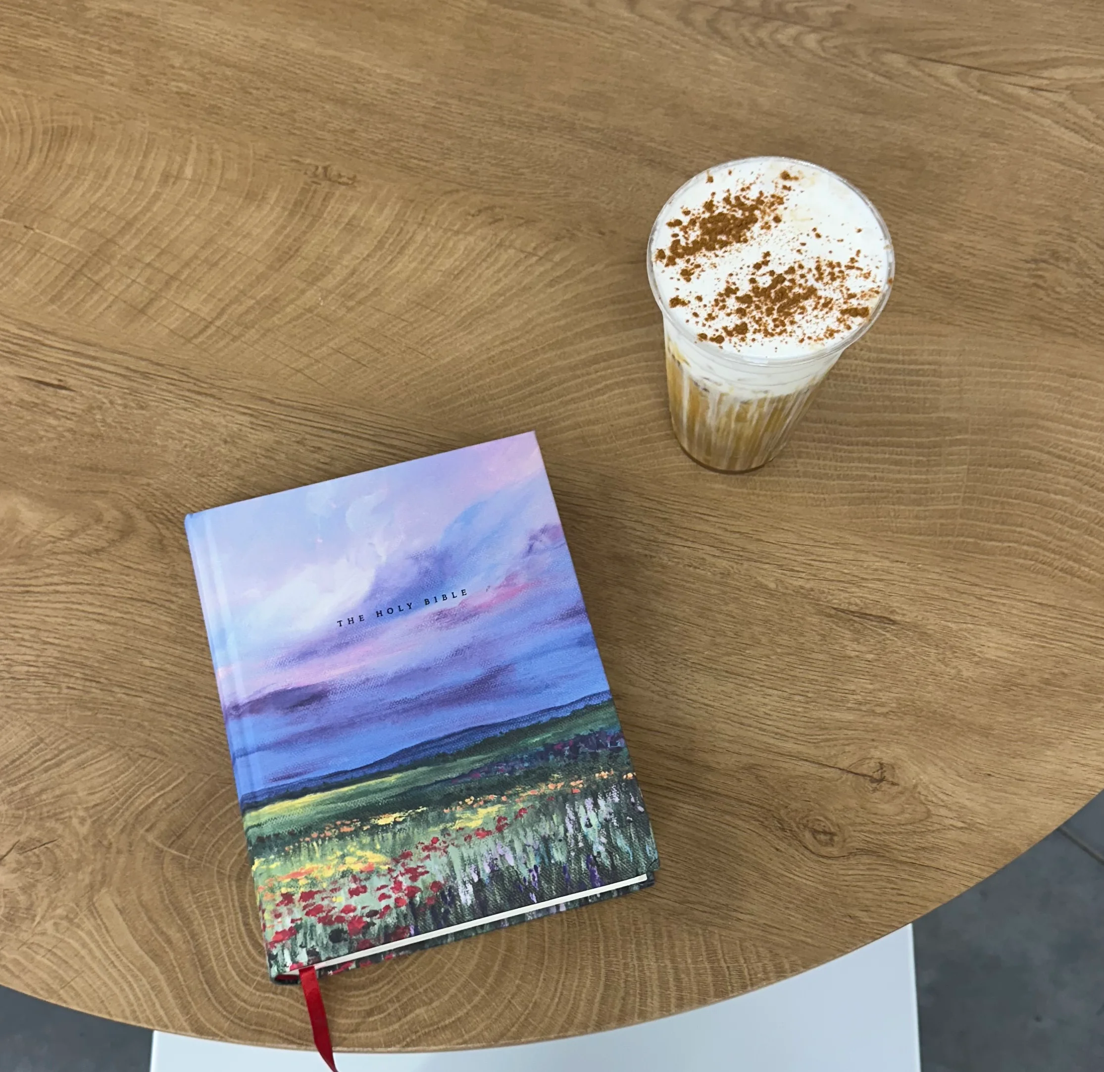 Coffee drink with whipped cream on a wooden table next to a journal