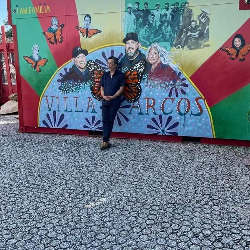 A person posing in front of the Villa Arcos mural