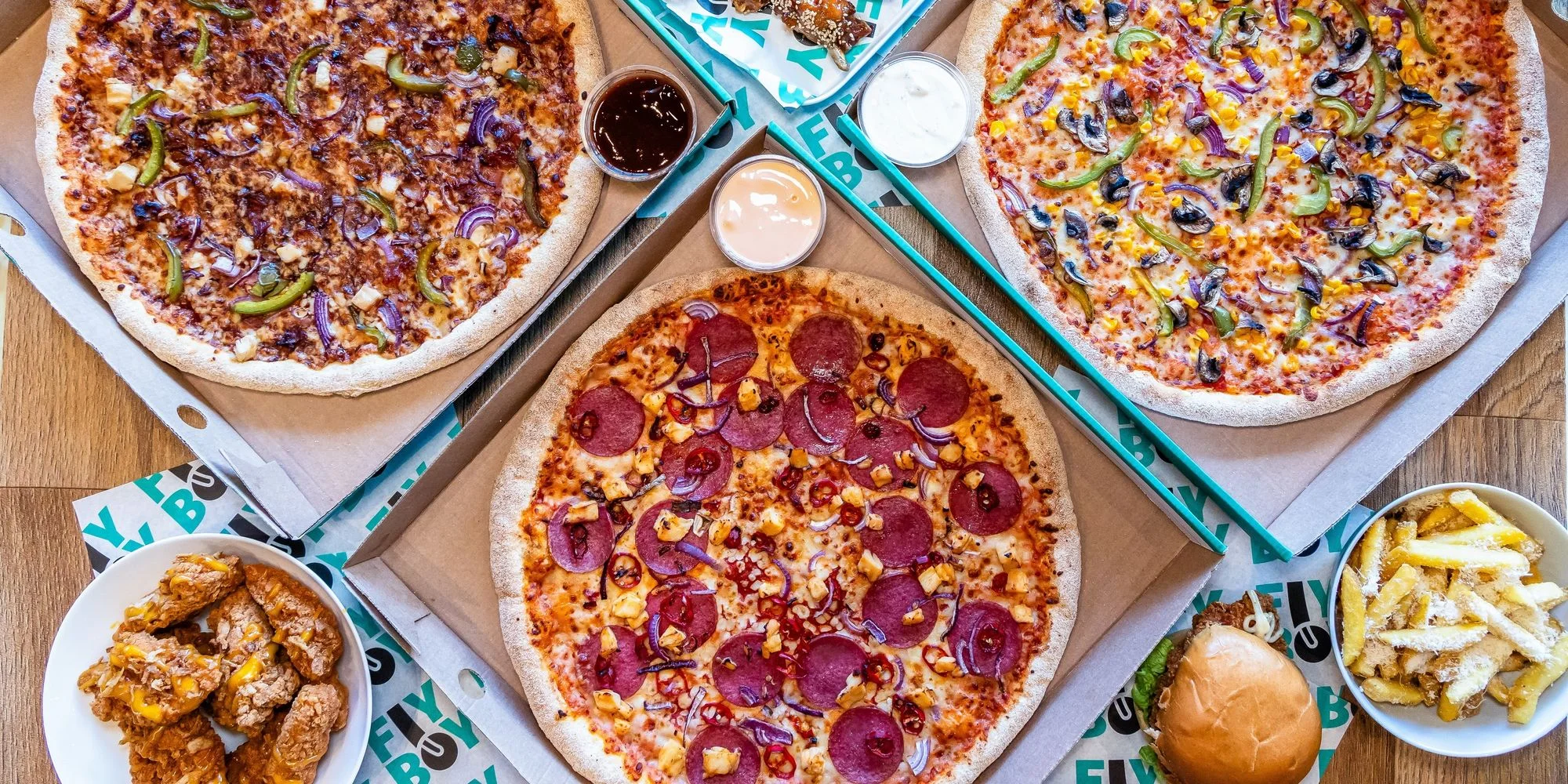 Assorted pizzas including pepperoni and veggie, with sides of chicken and fries
