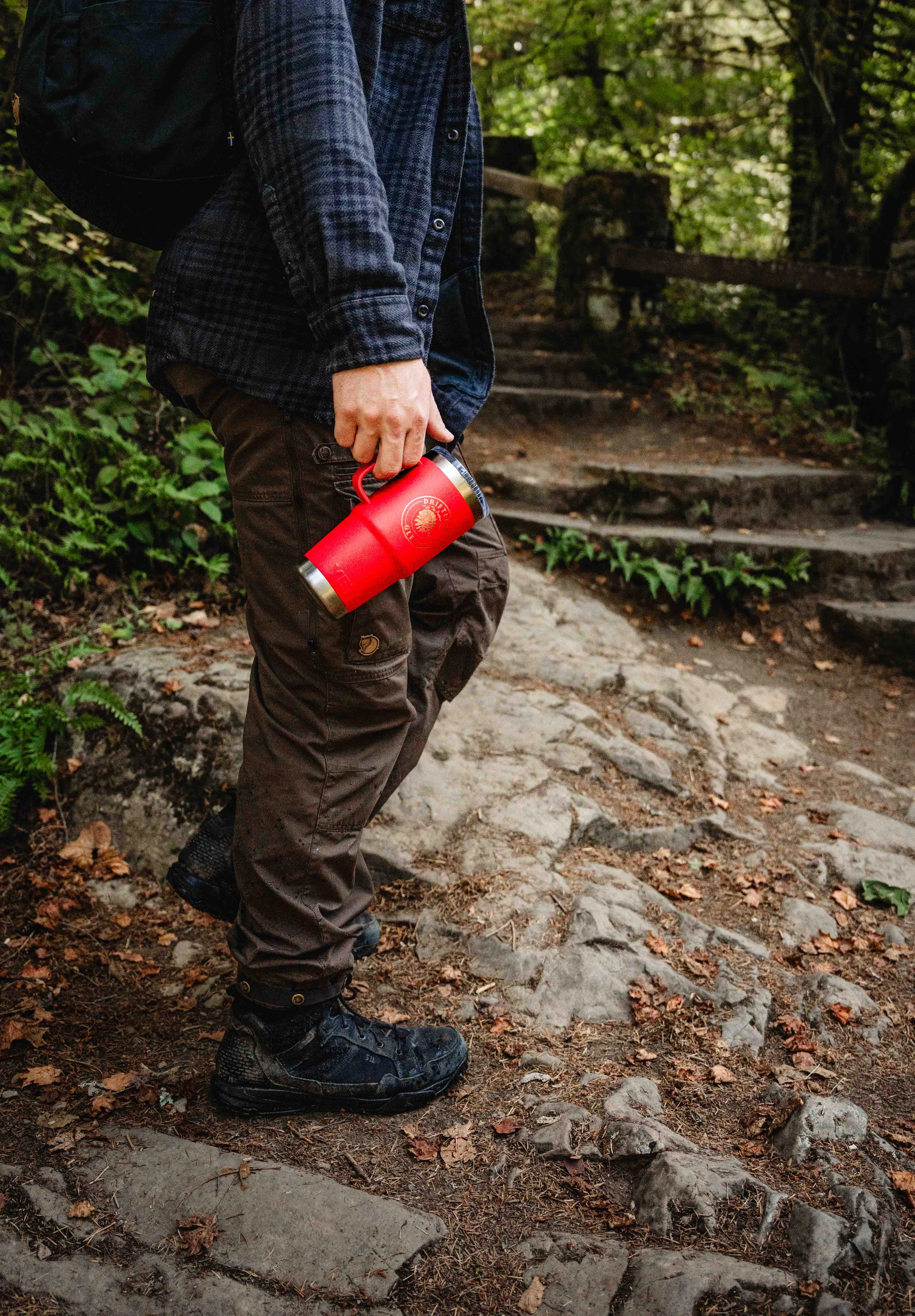 Someone walking in the woods carrying a 20 oz. Red YETI