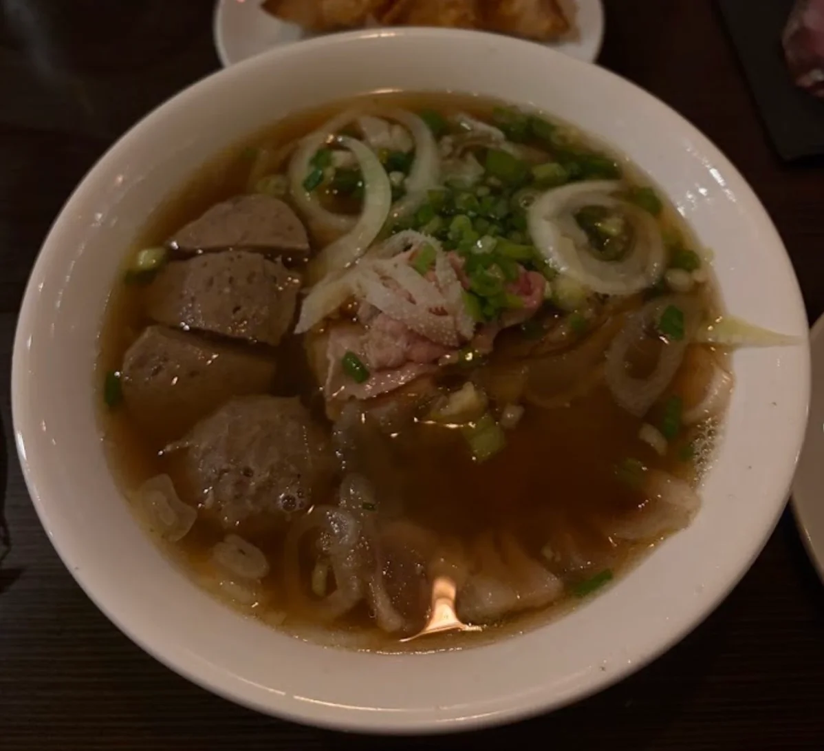Bowl of Vietnamese pho with meatballs and fresh herbs