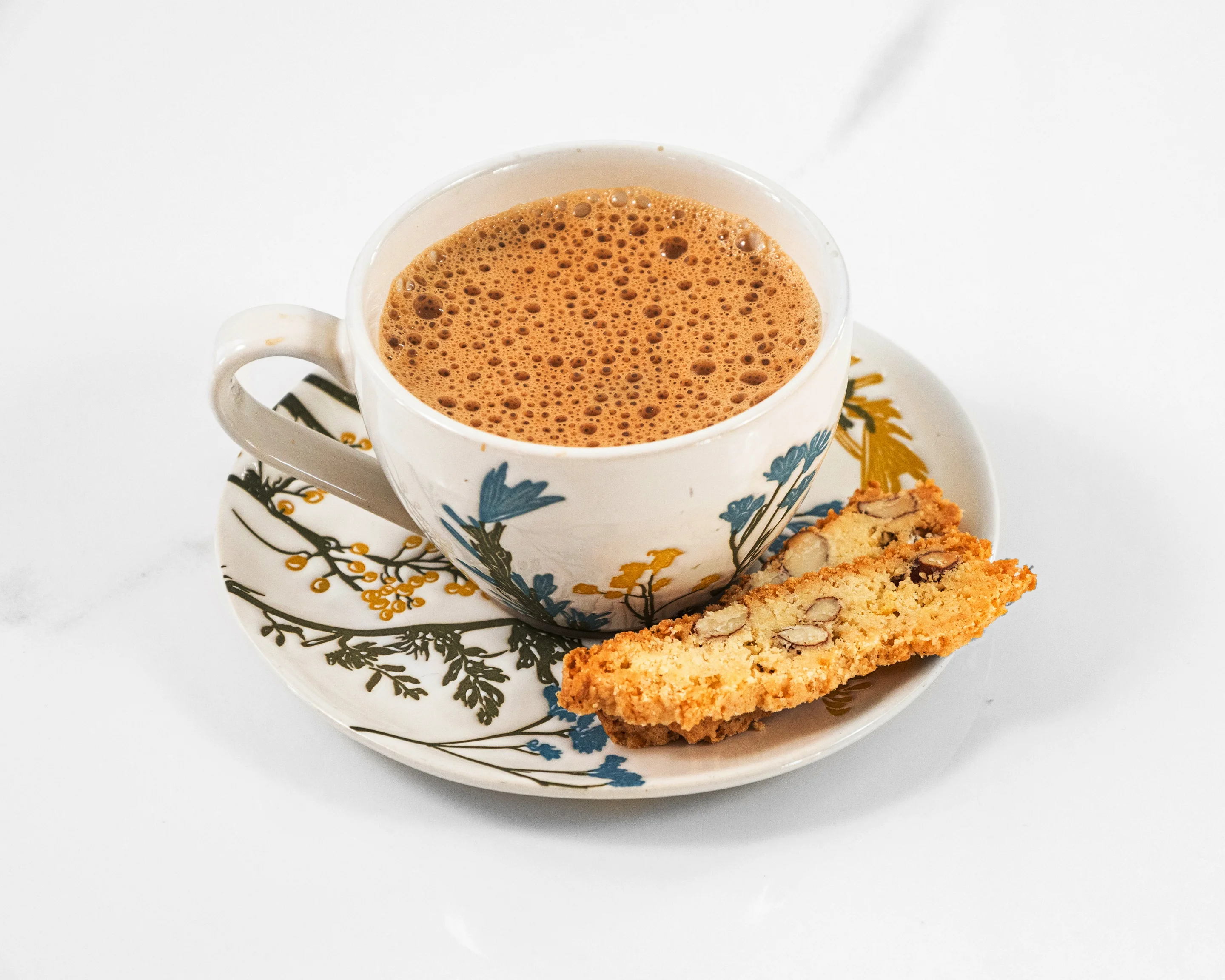 Cup of Indian chai with a biscuit on a floral saucer