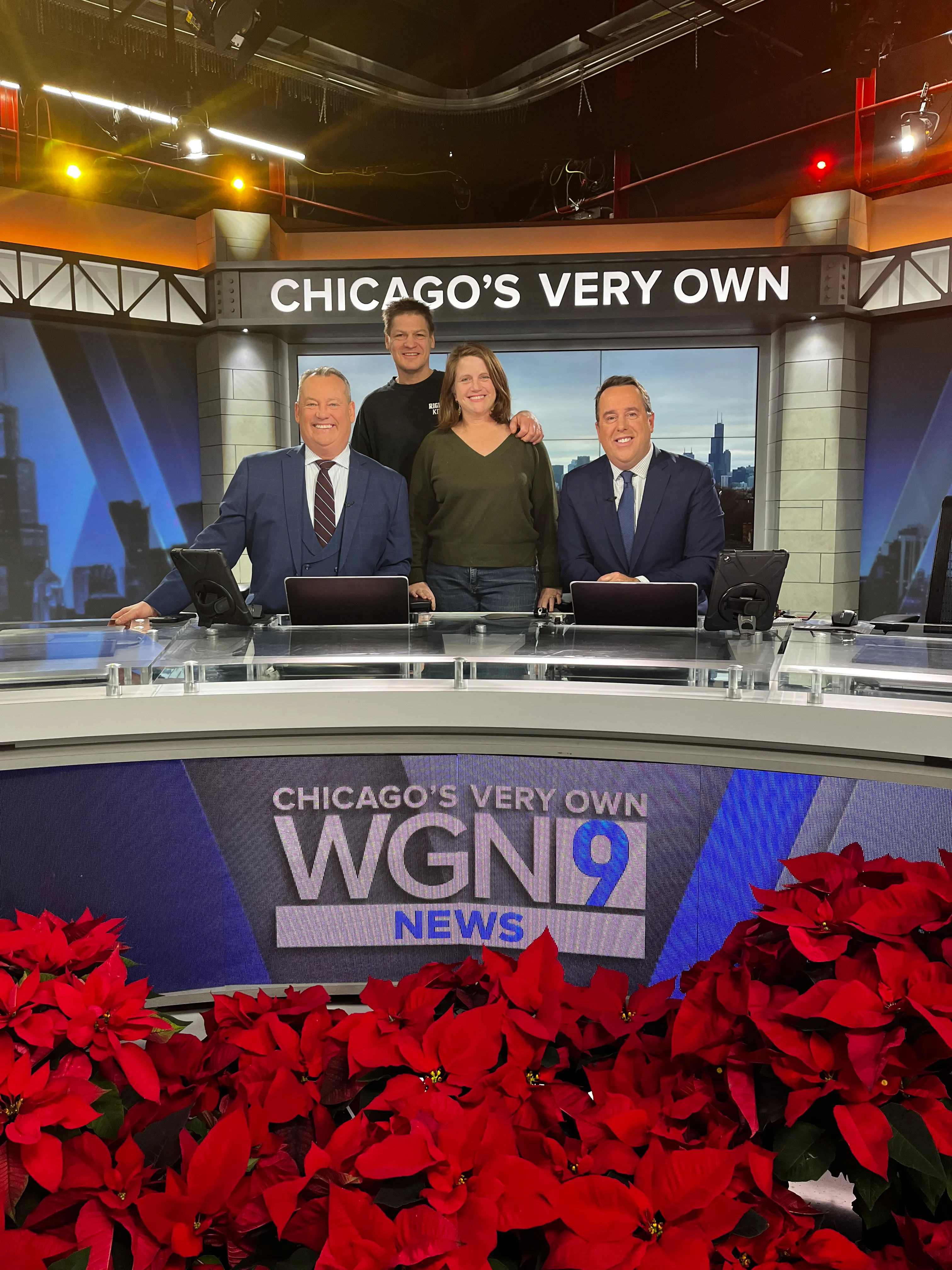News anchors at WGN 9 studio with festive poinsettias