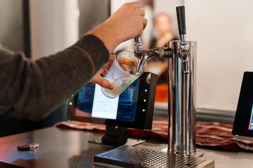 Bartender pouring a drink from a tap at a modern bar