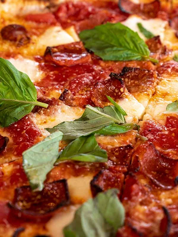 Close-up of a delicious basil pizza with fresh ingredients.