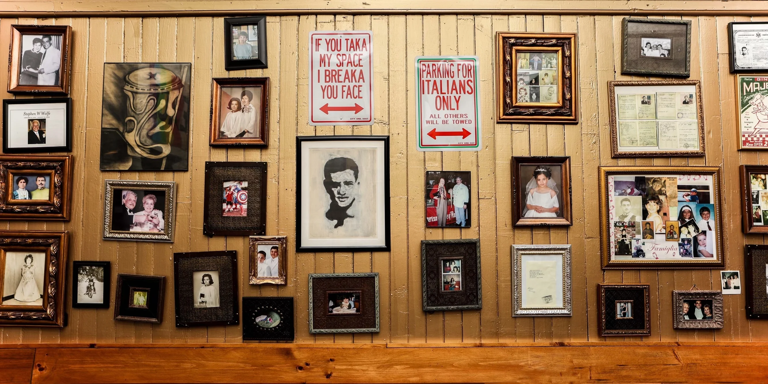 Decorative wall with framed photos and humorous signage in a cozy restaurant