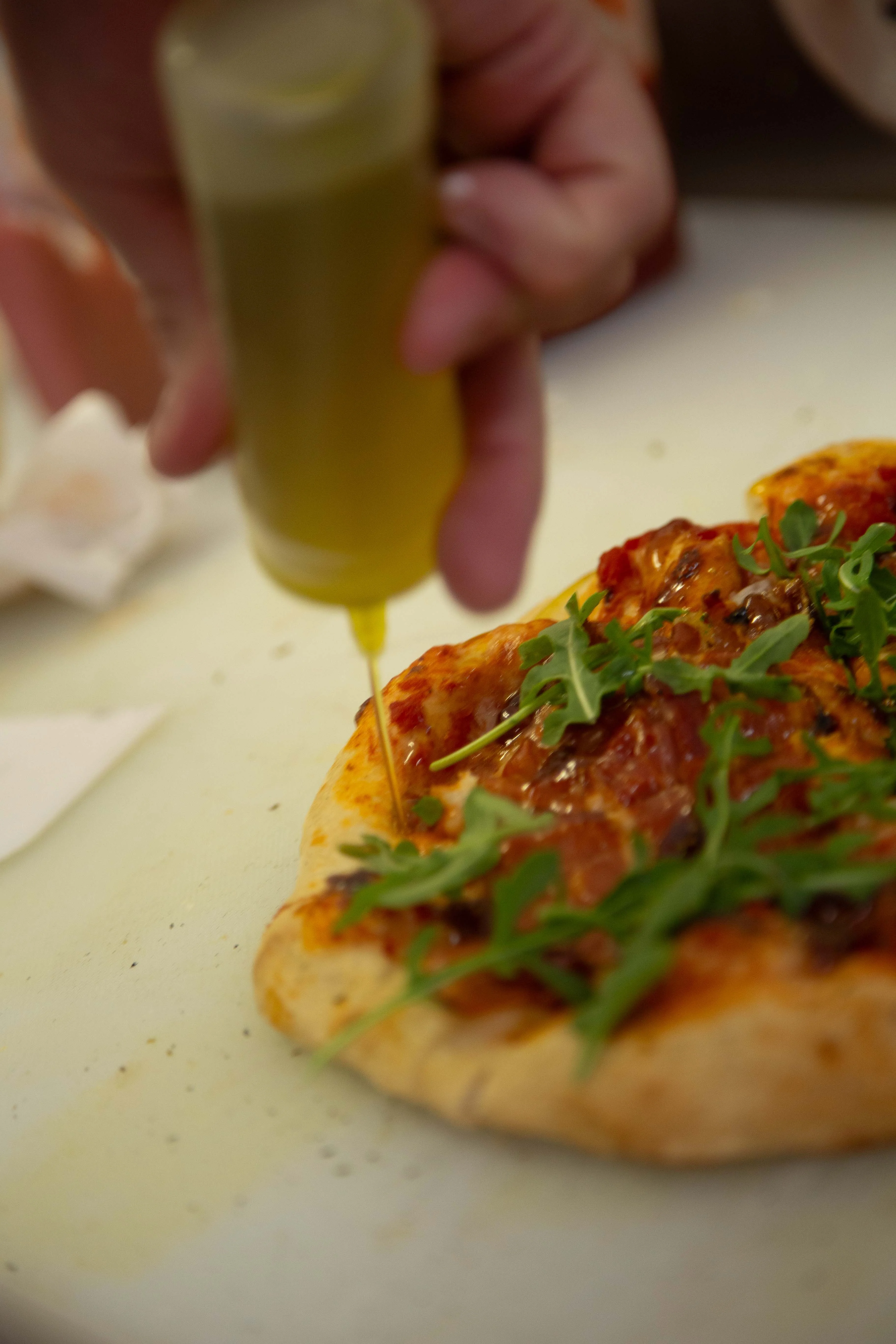 Drizzling olive oil on a freshly baked pizza
