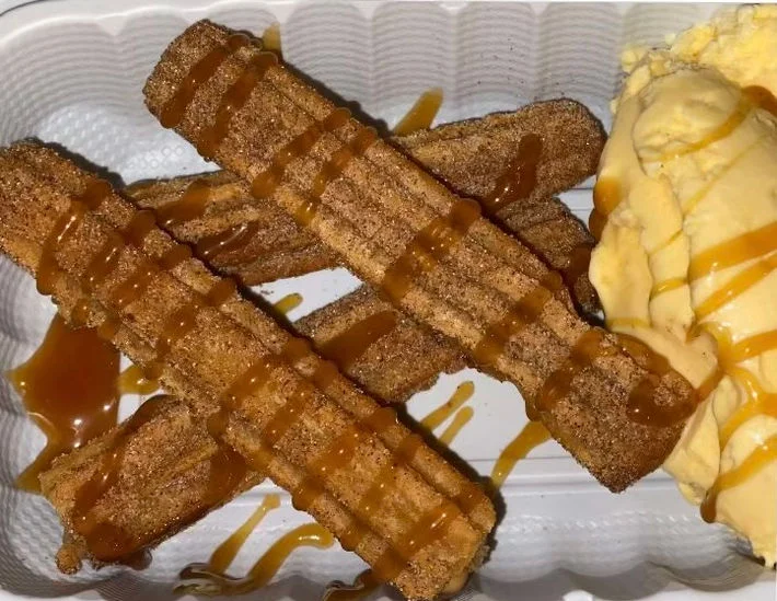 Churros drizzled with caramel sauce and served with vanilla ice cream