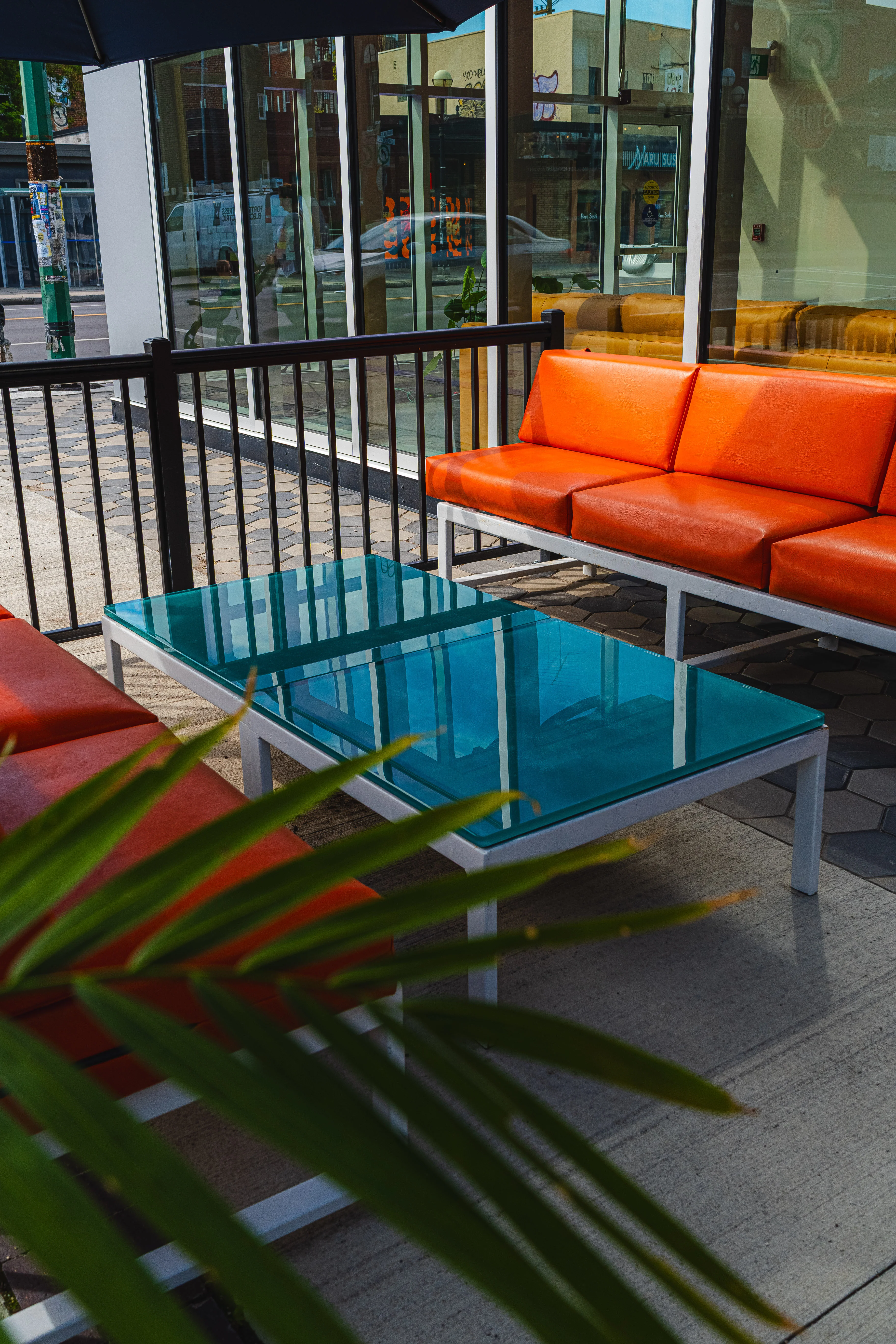 Outdoor seating area with vibrant orange couches and a glass table
