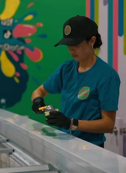 Employee preparing ice cream in a vibrant shop