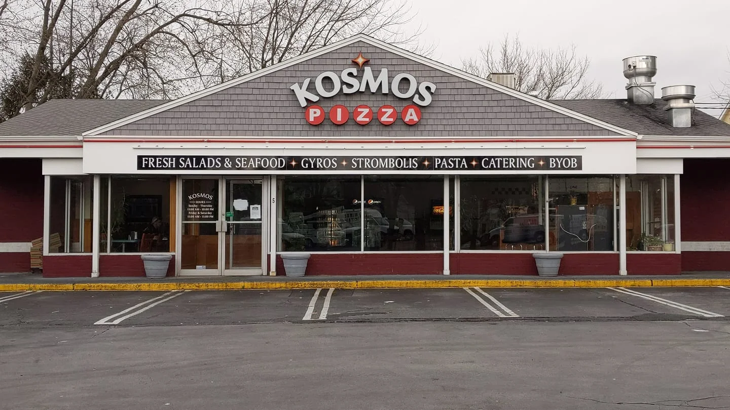 Exterior view of Kosmos Pizza restaurant with signage and parking area