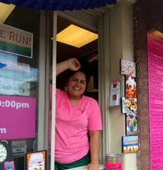 Friendly staff member at a colorful restaurant window
