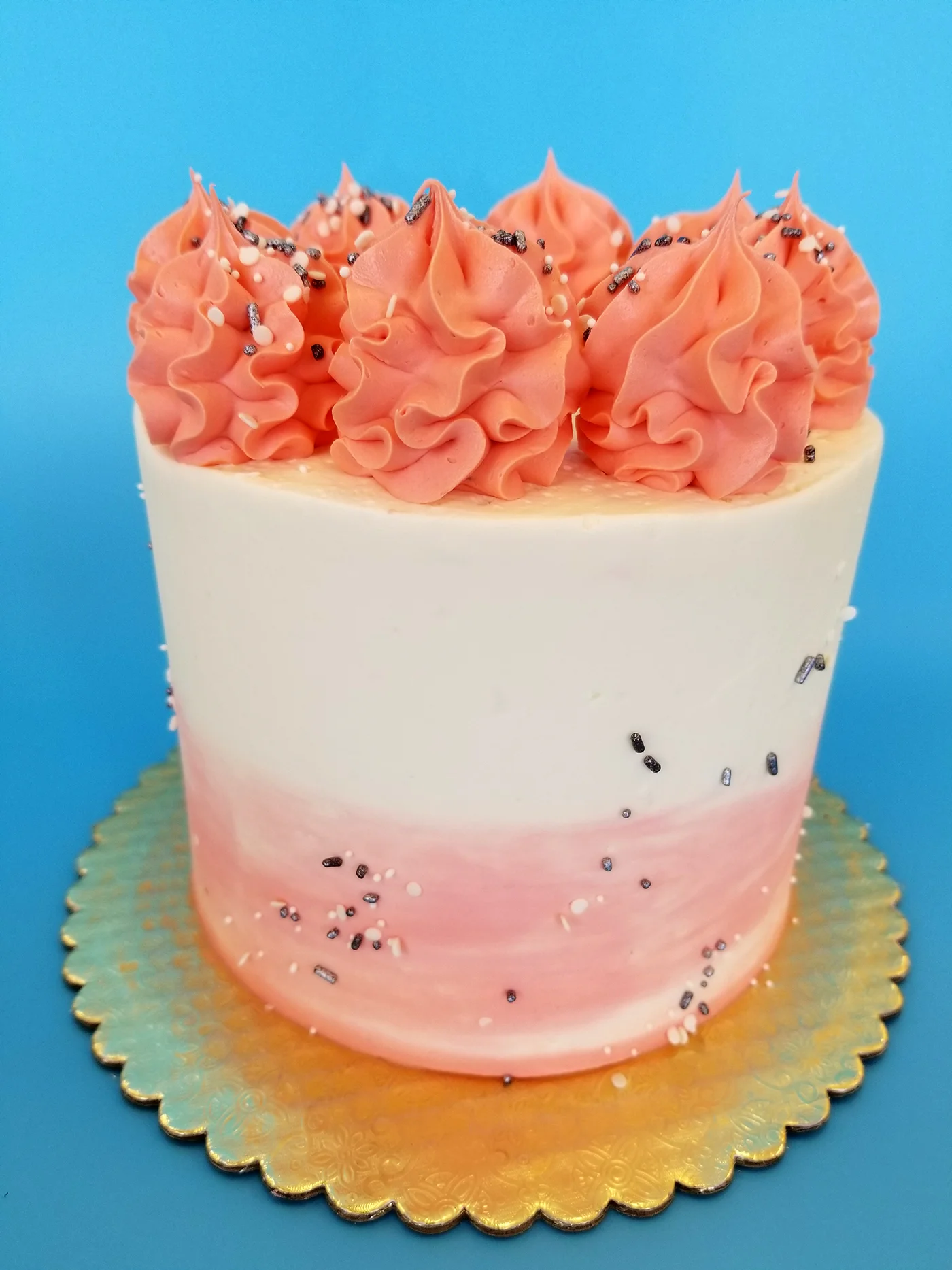 Elegant pink ombre cake with decorative frosting swirls