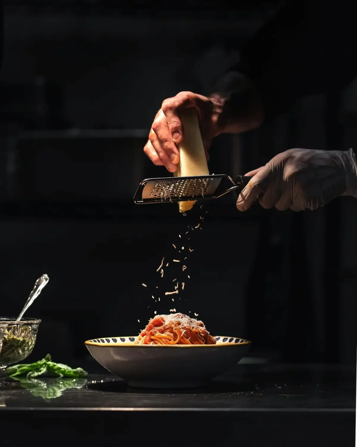 Grated Parmesan over classic spaghetti in a dark kitchen