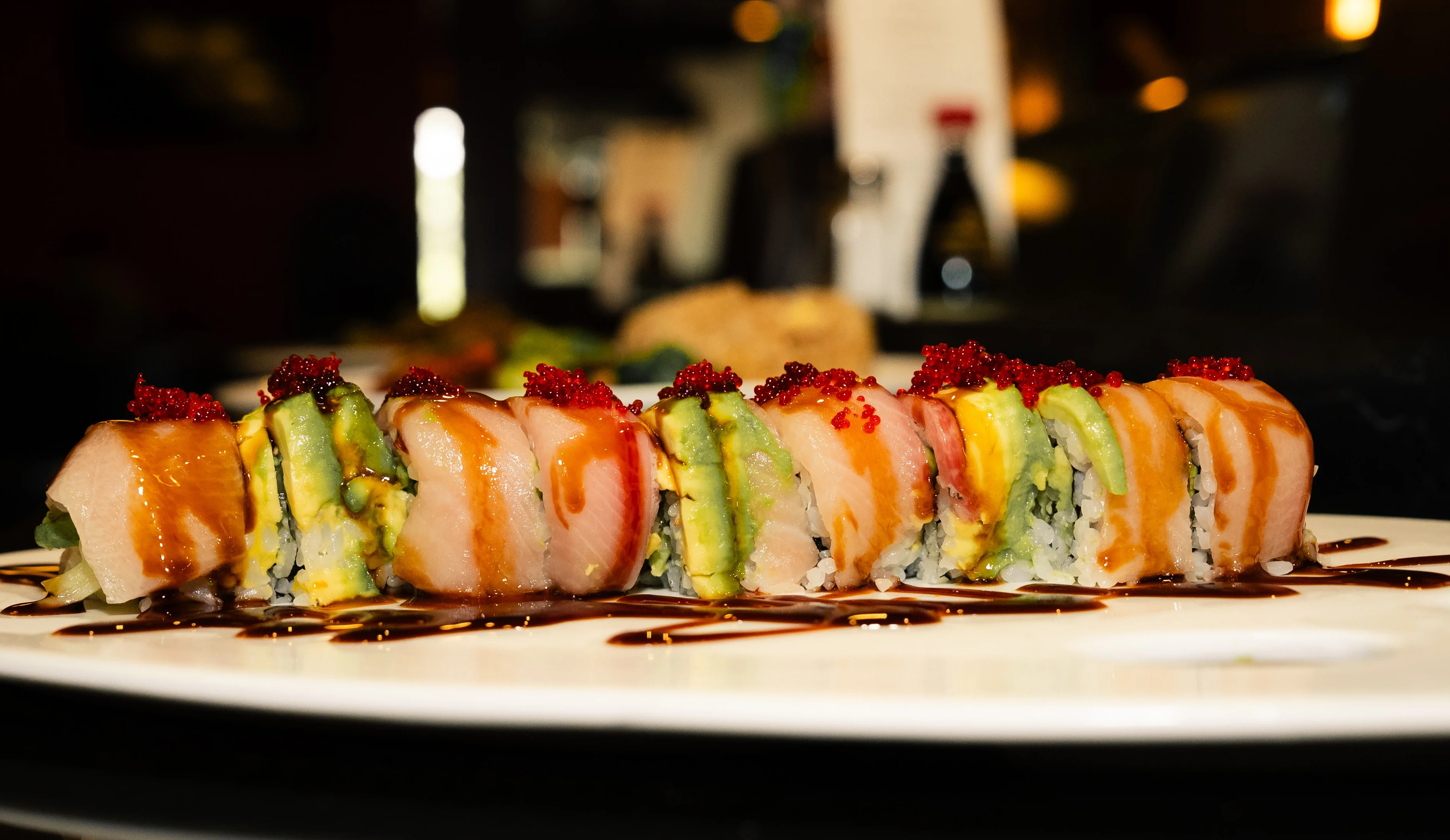 Colorful sushi rolls drizzled with sauce on a white plate