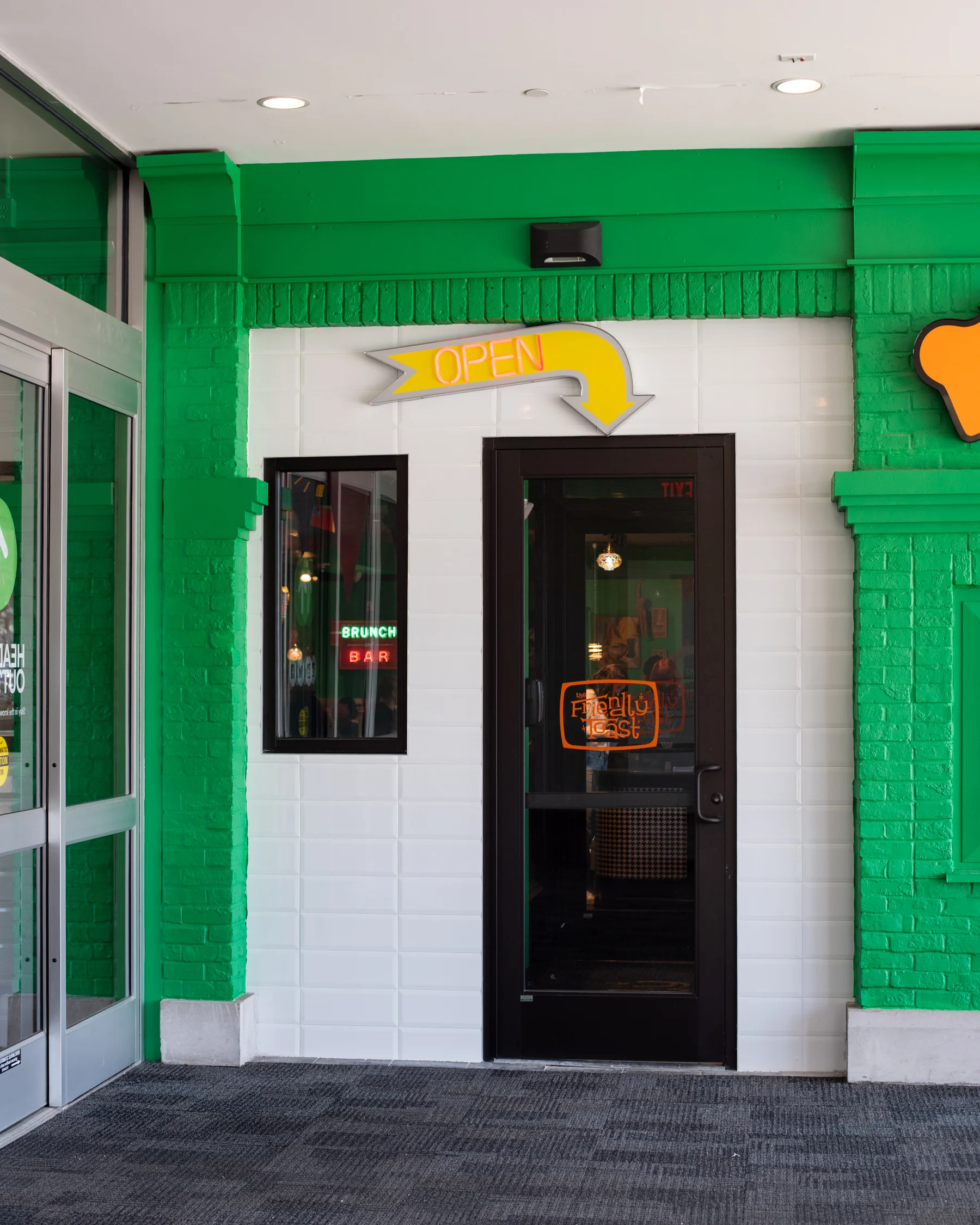 Brightly colored restaurant entrance with an open sign and modern decor