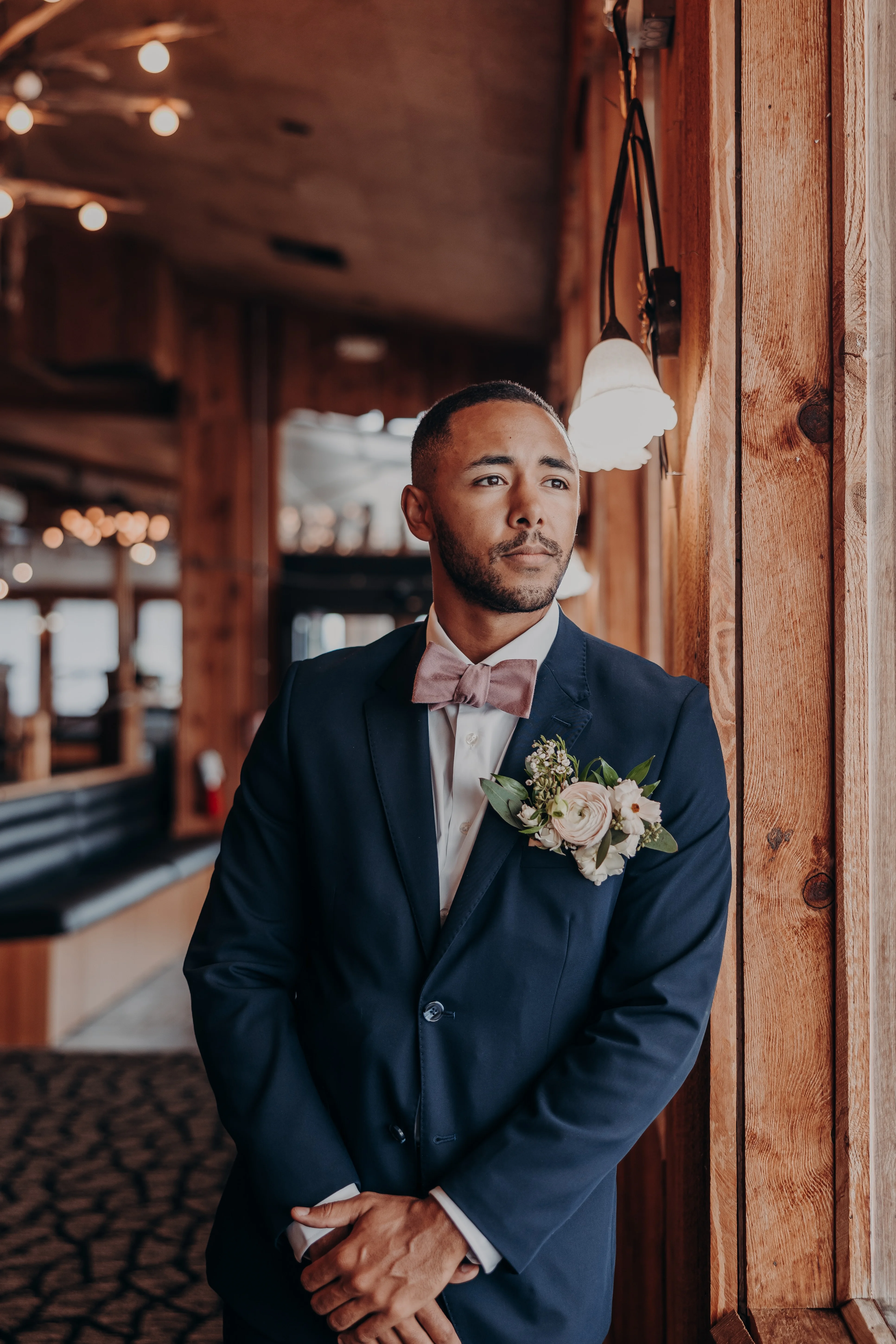 Groom in a navy suit with floral boutonniere in a rustic restaurant setting