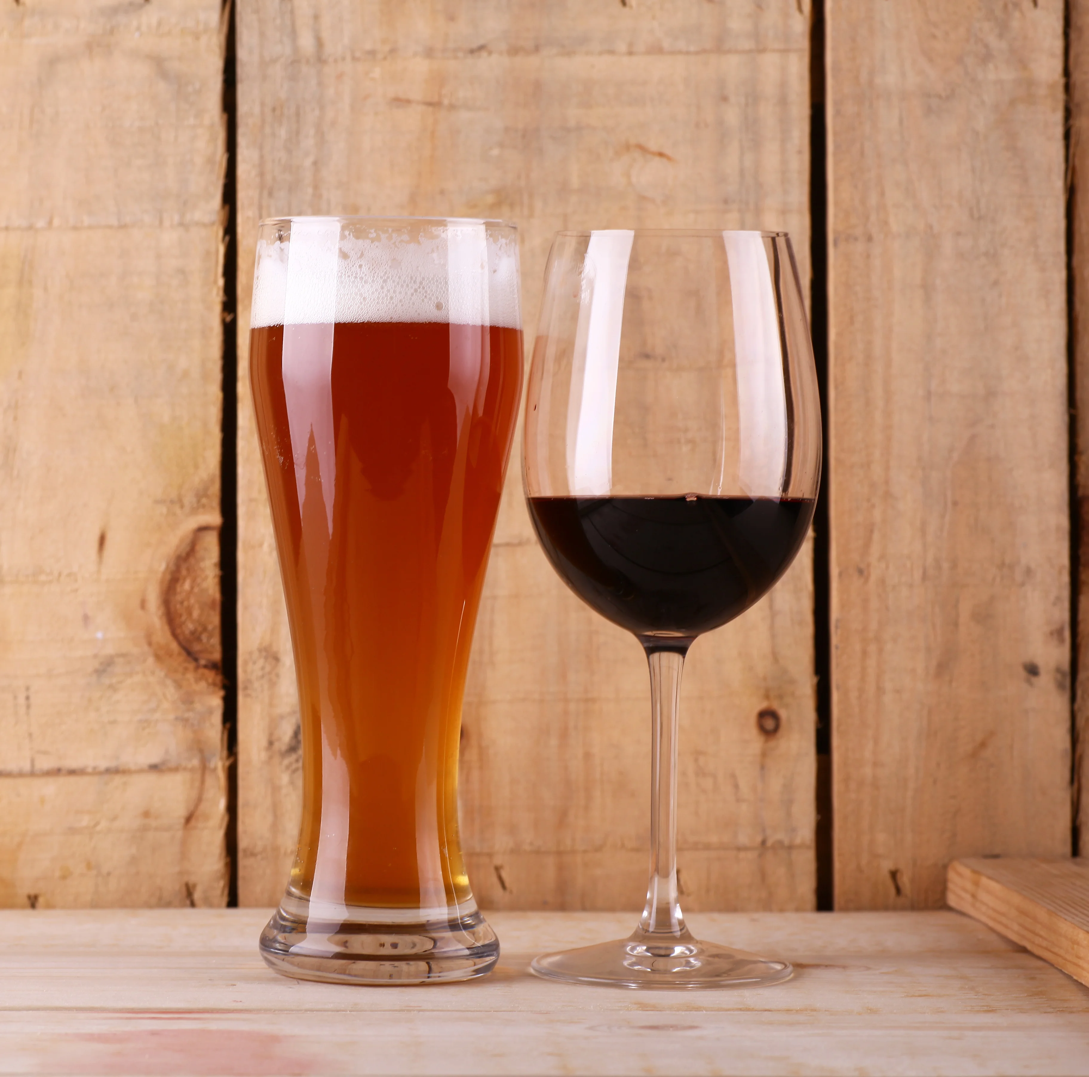 Craft beer and red wine served on a rustic wooden table