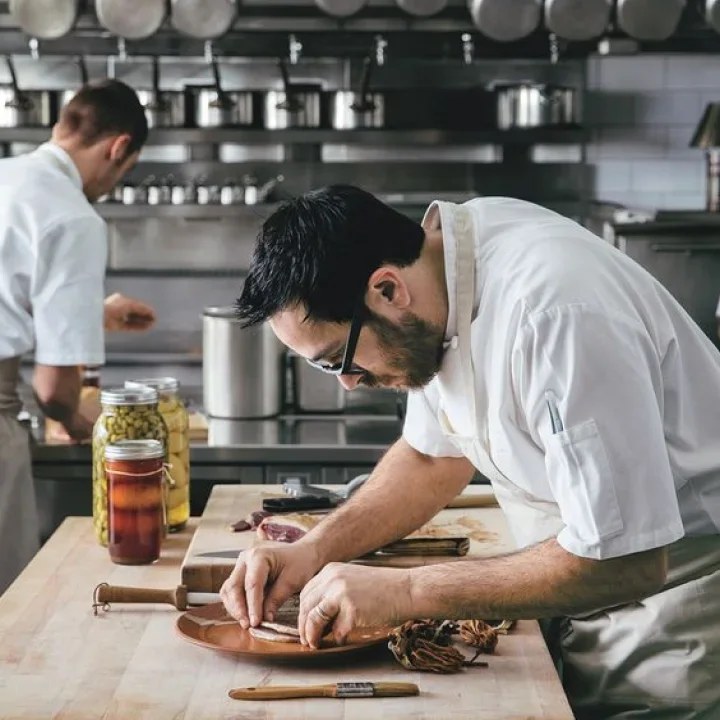 Chef meticulously plating a gourmet dish in a modern kitchen