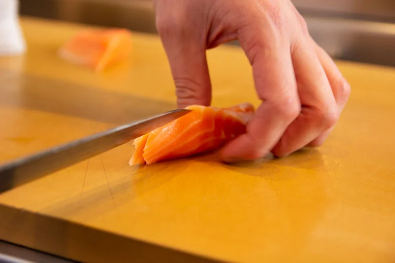Chef slicing fresh salmon for sushi preparation
