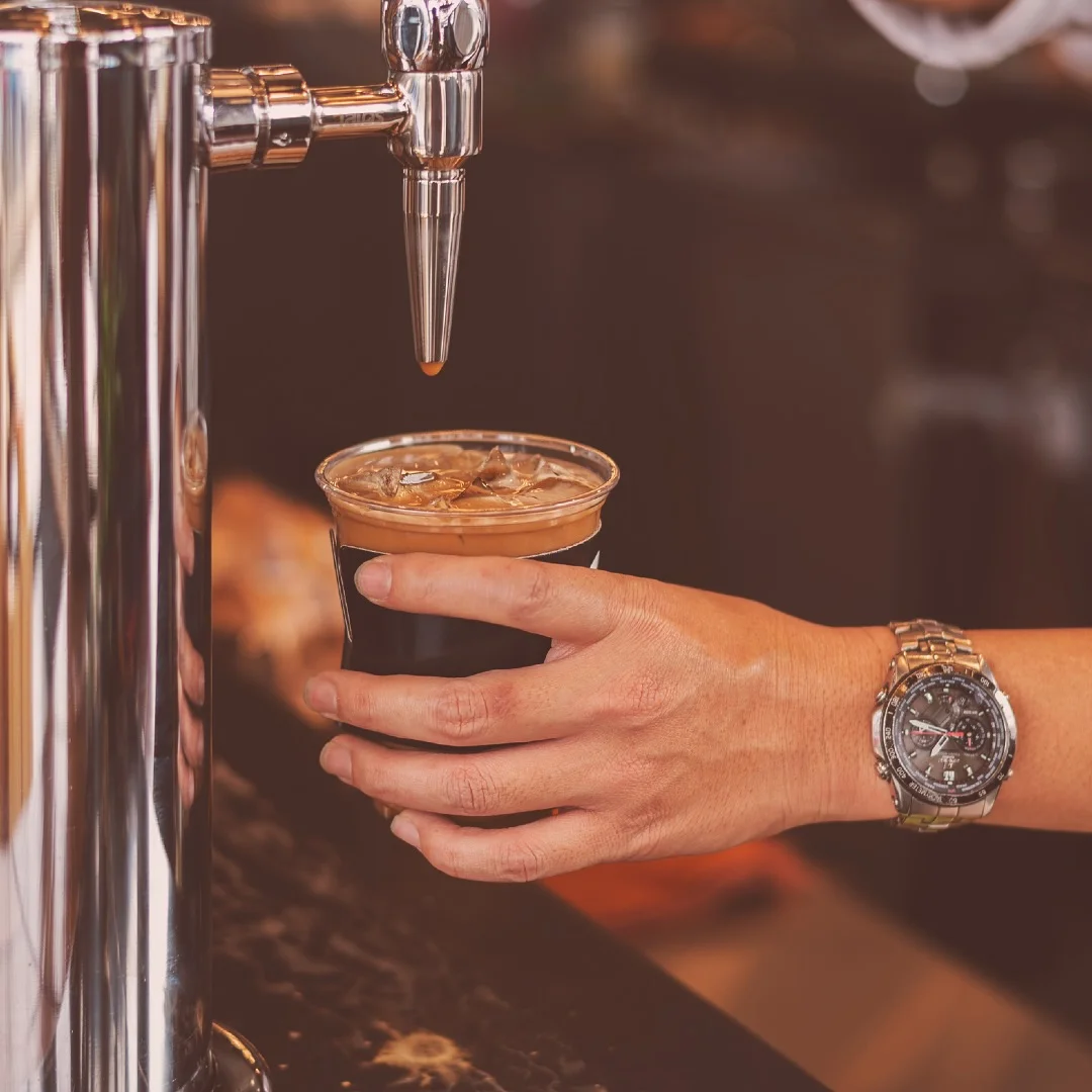 Barista pouring iced coffee from a tap