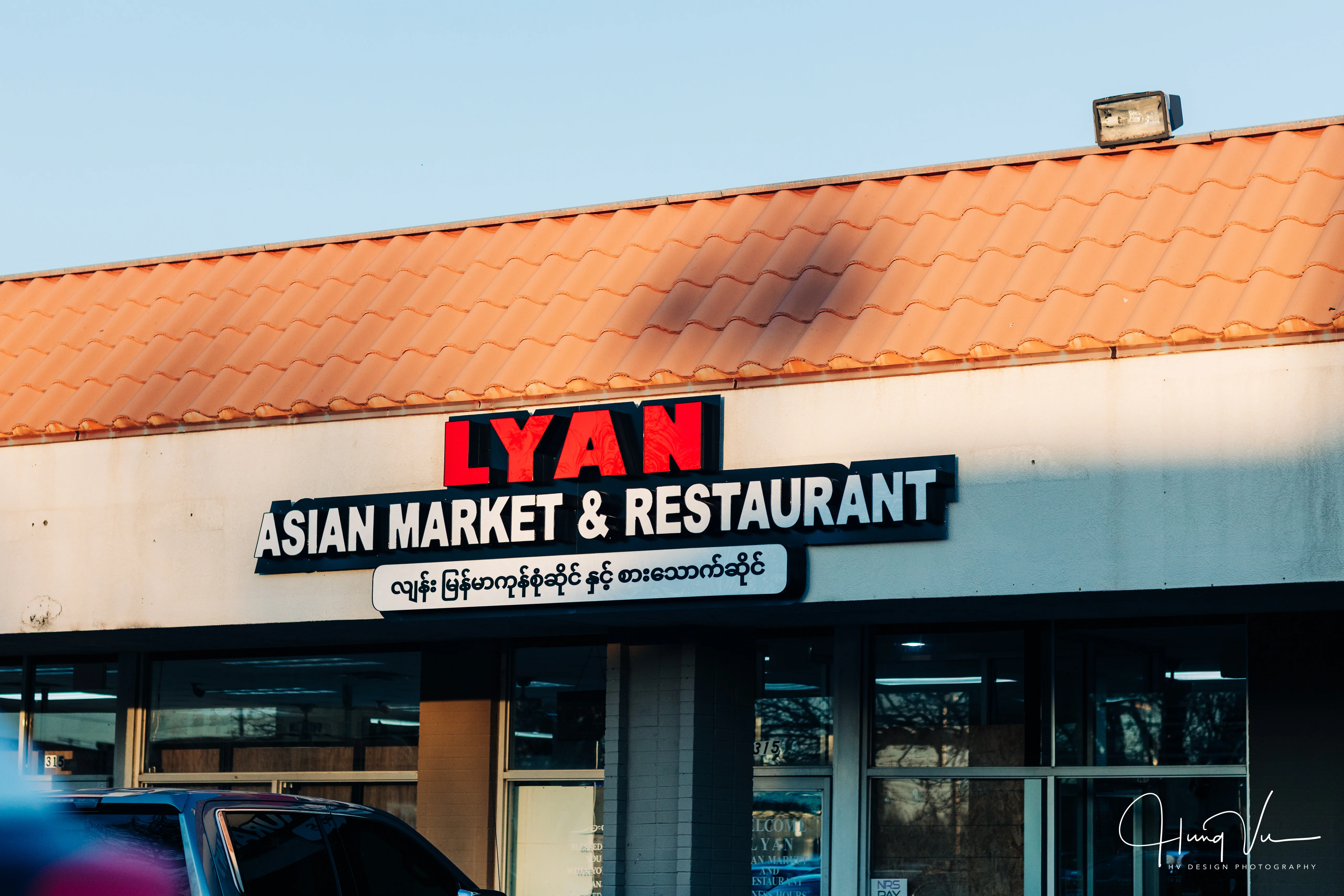 A shop sign displaying 'LYAN ASIAN MARKET & RESTAURANT' with a tiled roof in the background.