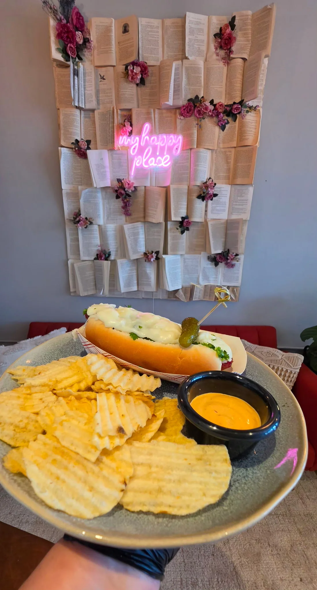 Delicious hot dog with chips and cheese sauce in a cozy restaurant setting