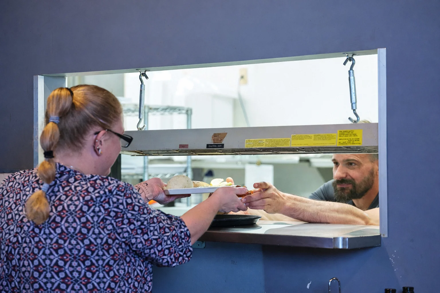 Server handing over a plate of food in a restaurant kitchen