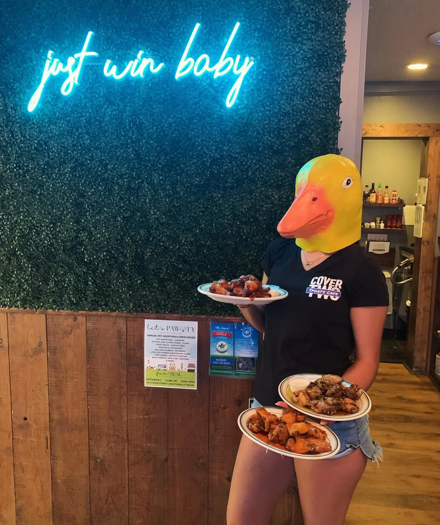 Person in duck mask holding plates of chicken wings