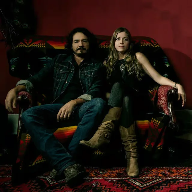 Stylish couple posing on a vintage sofa in a cozy setting