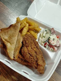 A takeout meal featuring two pieces of fried fish, crinkle-cut fries, a slice of bread, and a side salad with diced vegetables.