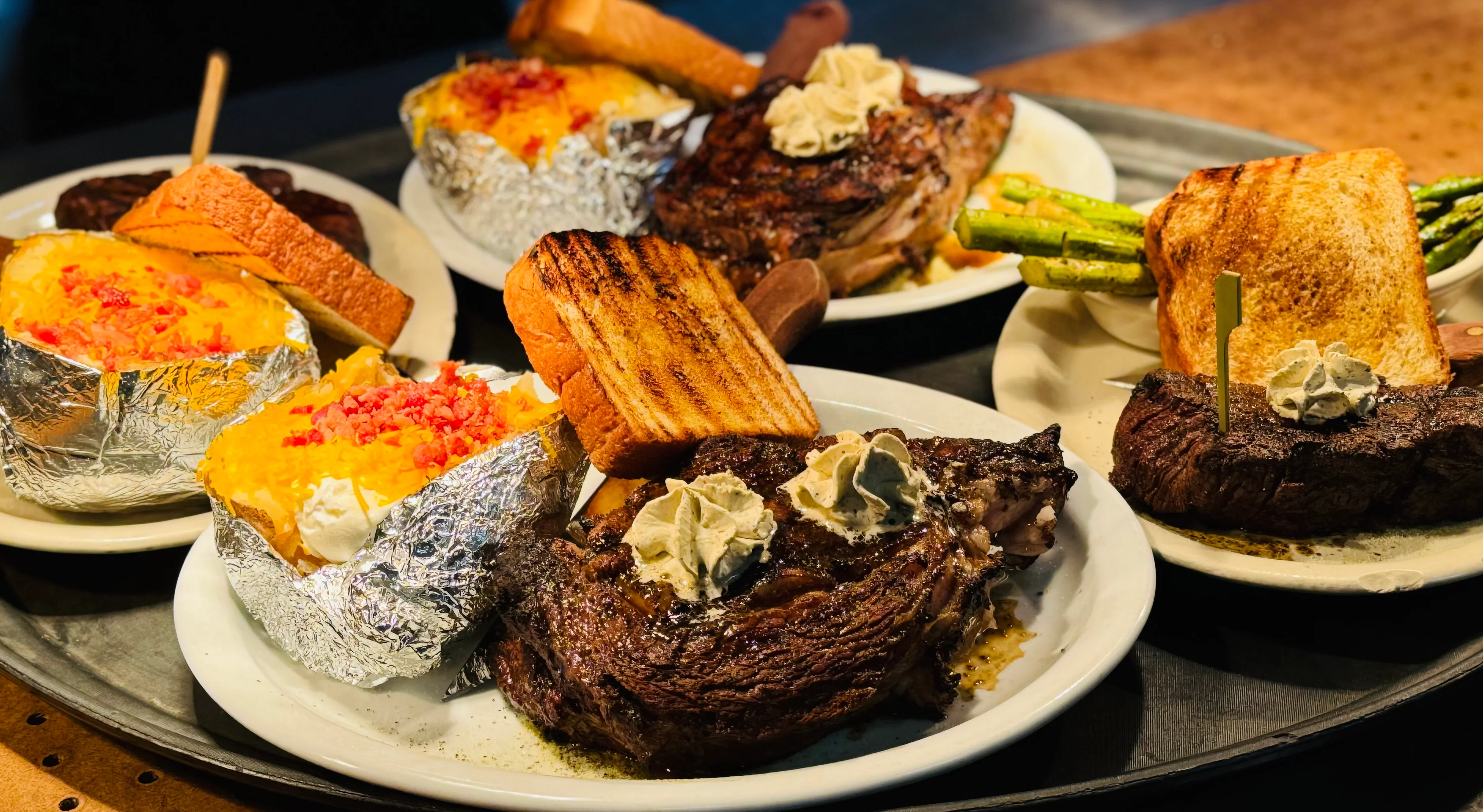 Grilled ribeye steak with loaded baked potatoes and toast